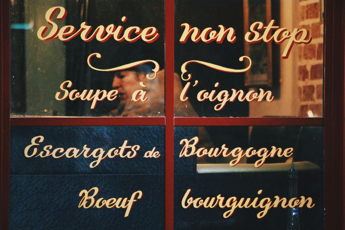 Elegant Parisian restaurant interior with burgundy velvet seating, candlelit tables, and classic French bistro ambiance