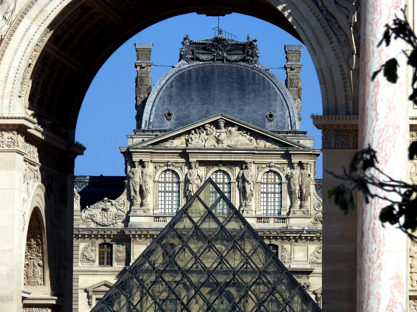 The Louvre pyramid framed by an arch of the palace in Paris